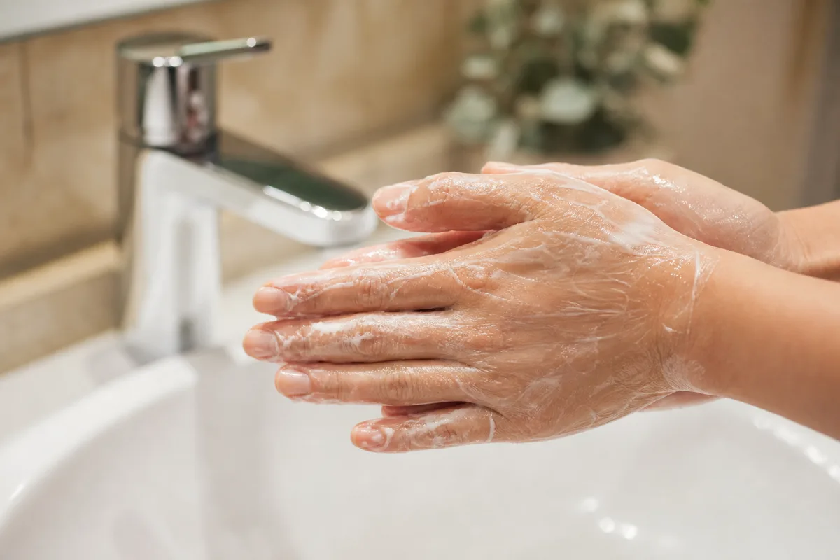 Mains émulsionnant une huile démaquillante avec un peu d&rsquo;eau au-dessus d&rsquo;un lavabo